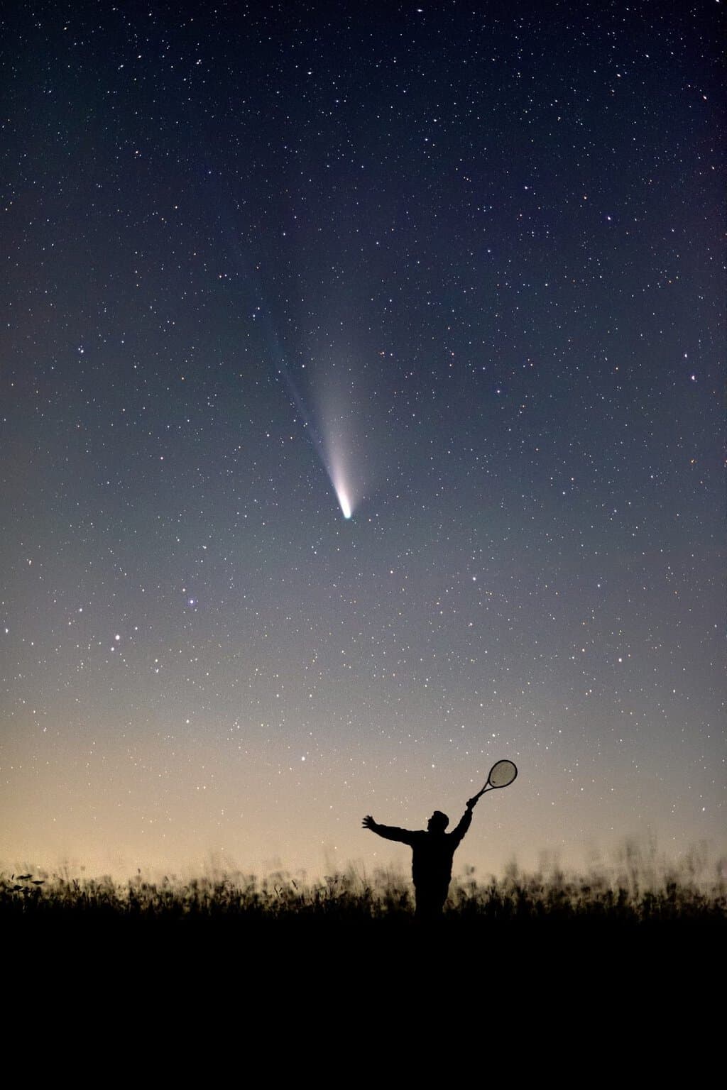 Comet NEOWISE with silhouette holding a tennis racket by Evgeni Tcherkasski
