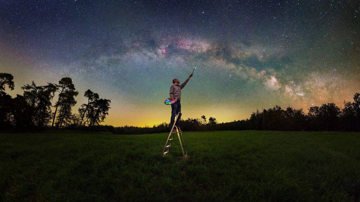 Person on a ladder painting the Milky Way — astrophotograph by Evgeni Tcherkasski
